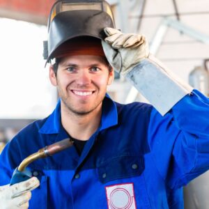 welder smiling while lifting protective face mask