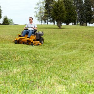 Person riding a zero turn lawn mower over grass