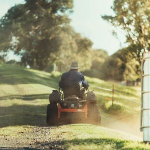 View from behind of a person riding on a zero turn lawn mower