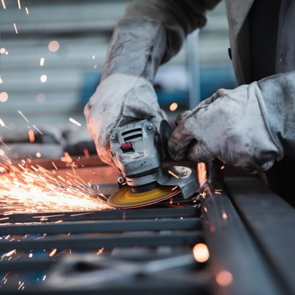 person wearing leather safety gloves uses metal grinder 